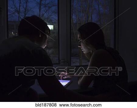 Stock Photo - Caucasian couple using digital tablet at night. Fotosearch