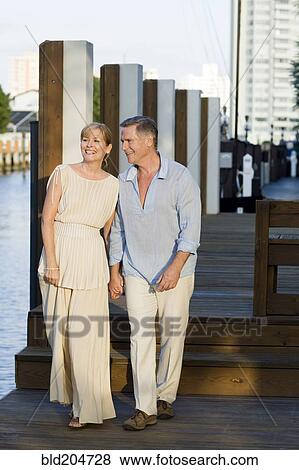 Stock Photo - Caucasian couple walking on dock. Fotosearch