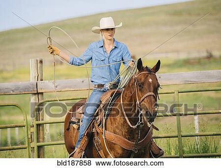 Stock Photo - Caucasian cowgirl throwing lasso on horseback. Fotosearch
