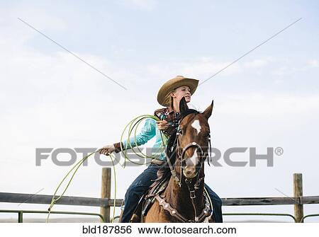Stock Photograph - Caucasian cowgirl throwing lasso on horseback. Fotosearch