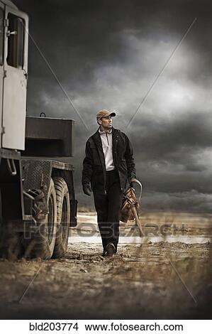Picture - Caucasian farmer walking by truck. Fotosearch