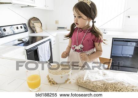 Stock Photography - Caucasian girl eating cereal in kitchen. Fotosearch