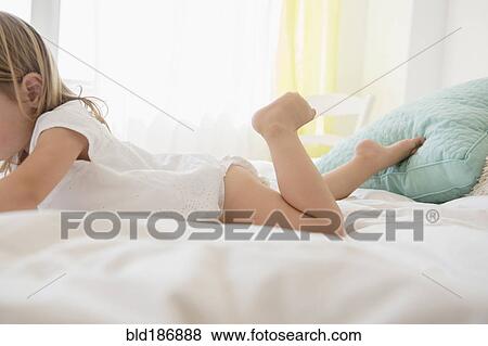 Stock Photo - Caucasian girl laying on bed. Fotosearch