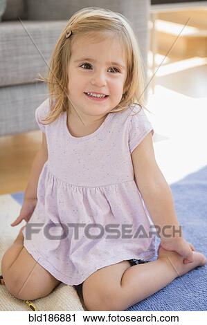 Stock Image - Caucasian girl sitting on floor. Fotosearch