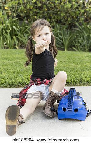 Picture - Caucasian girl sitting on skateboard. Fotosearch