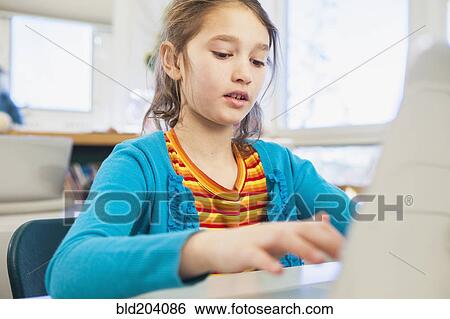 Stock Photograph - Caucasian girl using laptop in library. Fotosearch