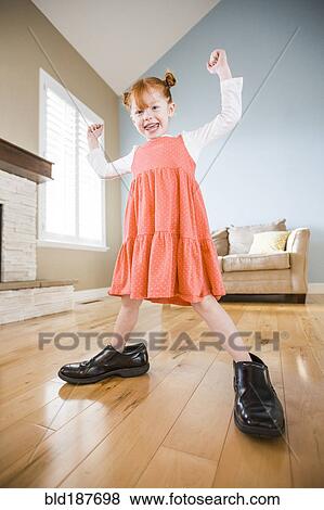 Caucasian girl wearing shoes of father in living room View Large Photo Image Stock Photo - Caucasian girl wearing shoes of father in living room. Fotosearch