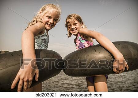 Stock Image - Caucasian girls with inner tubes in water. Fotosearch