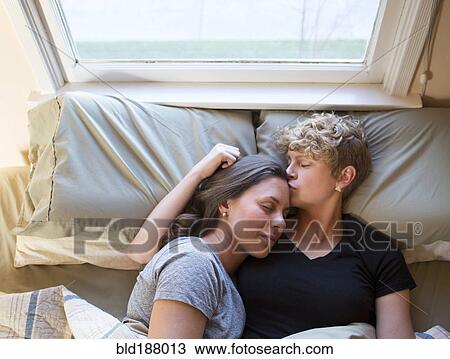 Stock Image - Caucasian lesbian couple kissing in bed. Fotosearch