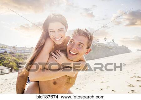 Caucasian man carrying girlfriend on beach View Large Photo Image Picture - Caucasian man carrying girlfriend on beach. Fotosearch