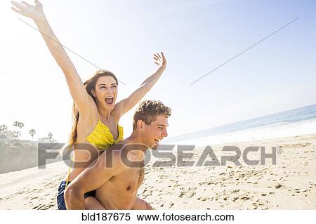 Caucasian man carrying girlfriend on beach View Large Photo Image Stock Photography - Caucasian man carrying girlfriend on beach. Fotosearch