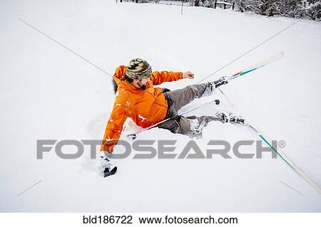 Stock Image - Caucasian man falling on cross-country skis in snow. Fotosearch