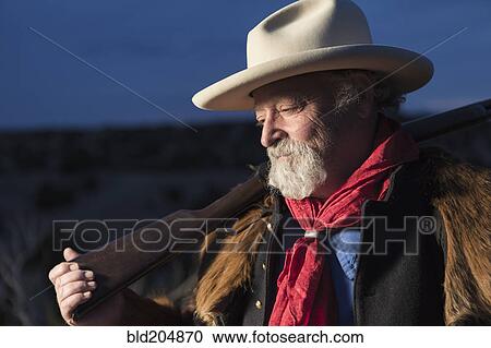Stock Image - Caucasian man holding gun outdoors. Fotosearch
