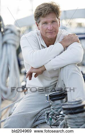 Stock Photo - Caucasian man sitting on sailboat. Fotosearch