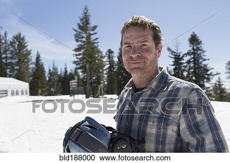 Stock Image - Caucasian man walking on snowy hilltop. Fotosearch