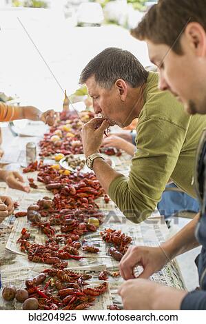 Stock Photography - Caucasian men eating at crawfish boil. Fotosearch