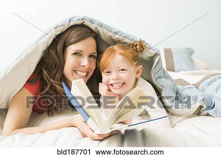 Caucasian mother and daughter reading book in bed View Large Photo Image Stock Image - Caucasian mother and daughter reading book in bed. Fotosearch