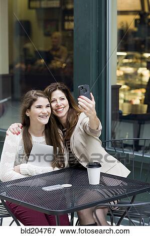 Caucasian mother and daughter taking picture in cafe View Large Photo Image Stock Photo - Caucasian mother and daughter taking picture in cafe. Fotosearch