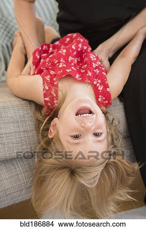 Picture - Caucasian mother tickling daughter on sofa. Fotosearch