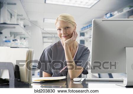 Stock Image - Caucasian nurse working at computer in hospital. Fotosearch