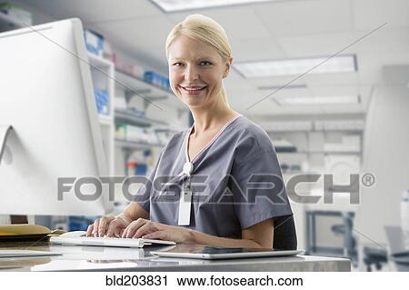 Stock Image - Caucasian nurse working at computer in hospital. Fotosearch