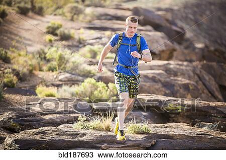 Stock Image - Caucasian teenage boy running on rock formation. Fotosearch