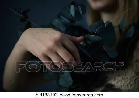 Stock Image - Caucasian teenage girl holding plants. Fotosearch