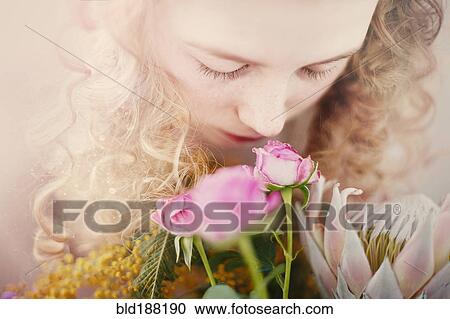 Stock Image - Caucasian teenage girl smelling bouquet of flowers. Fotosearch