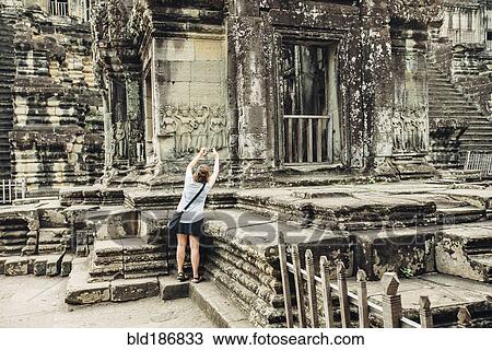 Stock Image - Caucasian tourist photographing Angkor Wat ruins, Siem Reap, Cambodia. Fotosearch