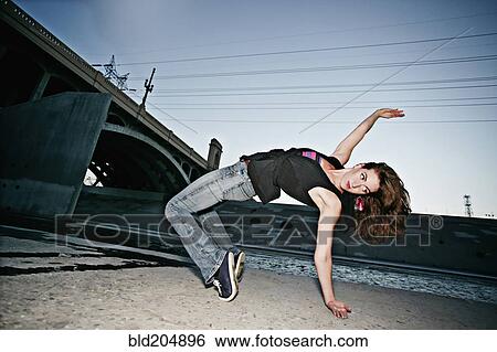 Stock Photograph - Caucasian woman break dancing under overpass. Fotosearch