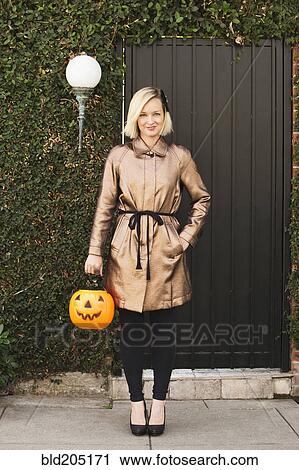 Stock Image - Caucasian woman carrying jack o' lantern bucket. Fotosearch