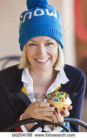 Stock Photo - Caucasian woman eating cupcake. Fotosearch