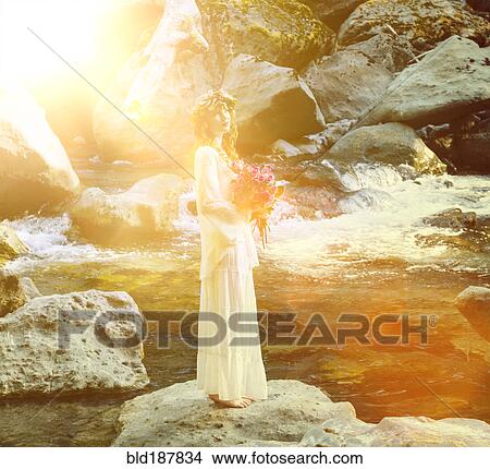 Picture - Caucasian woman holding bouquet of flowers at river. Fotosearch