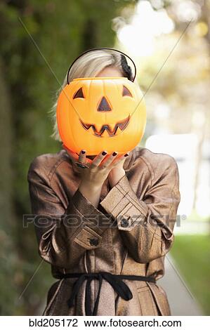 Stock Image - Caucasian woman holding jack o' lantern bucket. Fotosearch