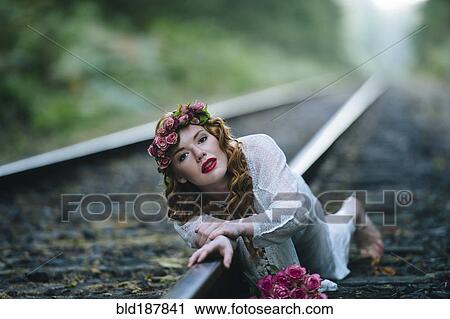 Stock Image - Caucasian woman laying on train tracks. Fotosearch