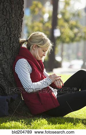 Stock Photo - Caucasian woman leaning against tree in park. Fotosearch