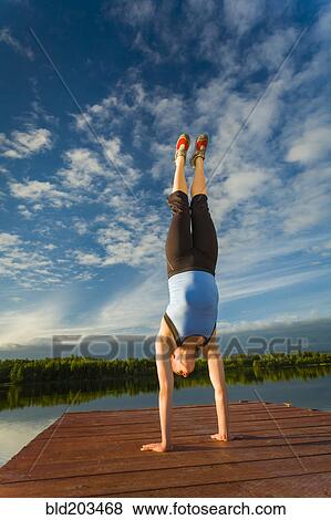 Stock Photo - Caucasian woman practicing yoga on dock on still lake, Anchorage, Alaska, United States. Fotosearch