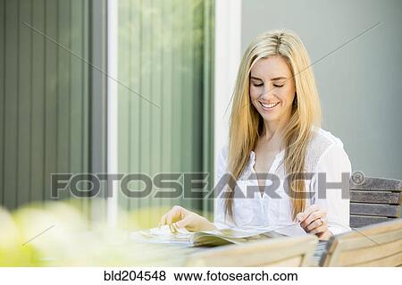 Caucasian woman reading magazine outdoors View Large Photo Image Stock Photo - Caucasian woman reading magazine outdoors. Fotosearch