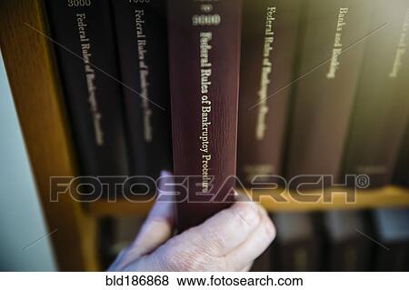 Stock Photo - Caucasian woman selecting reference book from shelf. Fotosearch