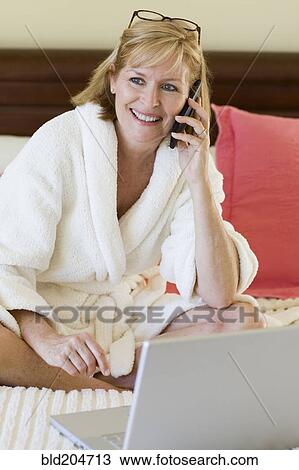 Caucasian woman talking on cell phone on bed View Large Photo Image Stock Image - Caucasian woman talking on cell phone on bed. Fotosearch