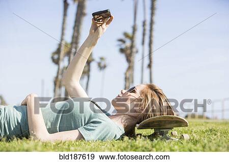Stock Photo - Caucasian woman using cell phone in park. Fotosearch
