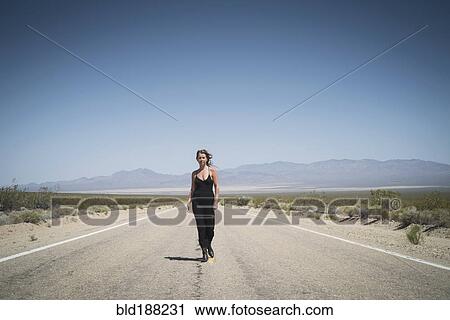 Caucasian woman walking on remote desert road View Large Photo Image Stock Image - Caucasian woman walking on remote desert road. Fotosearch