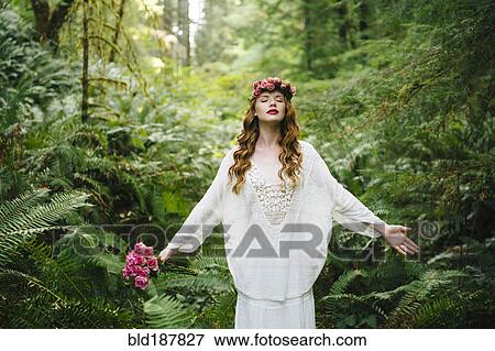 Stock Photo - Caucasian woman wearing flower crown in forest. Fotosearch
