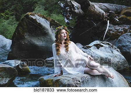 Caucasian woman wearing flower crown on rock at river View Large Photo Image Stock Image - Caucasian woman wearing flower crown on rock at river. Fotosearch