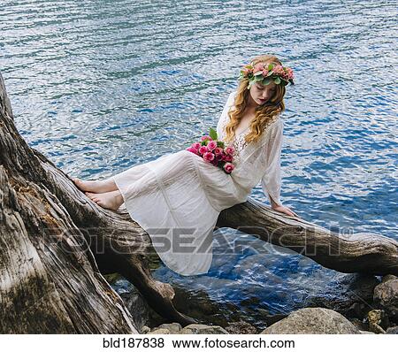 Caucasian woman wearing flower crown on log at river View Large Photo Image Stock Photo - Caucasian woman wearing flower crown on log at river. Fotosearch