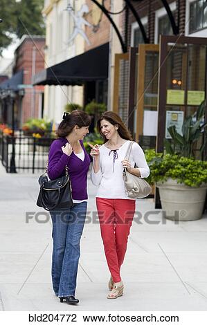 Stock Image - Caucasian women talking on city street. Fotosearch