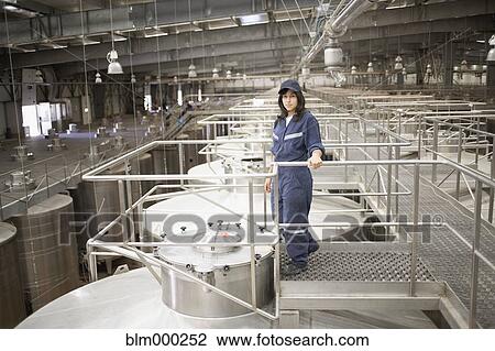 Stock Image - Chilean woman standing by vat at winery. Fotosearch
