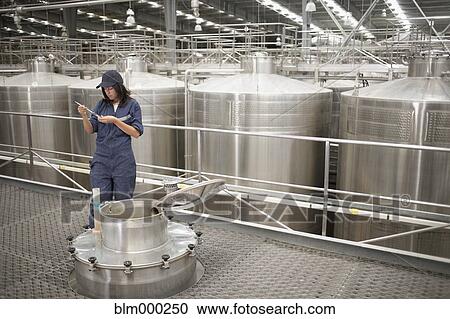 Stock Image - Chilean woman testing wine from vat at winery. Fotosearch