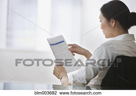 Stock Image - Chinese businesswoman reviewing document. Fotosearch
