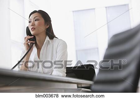 Stock Photo - Chinese businesswoman using telephone in office. Fotosearch